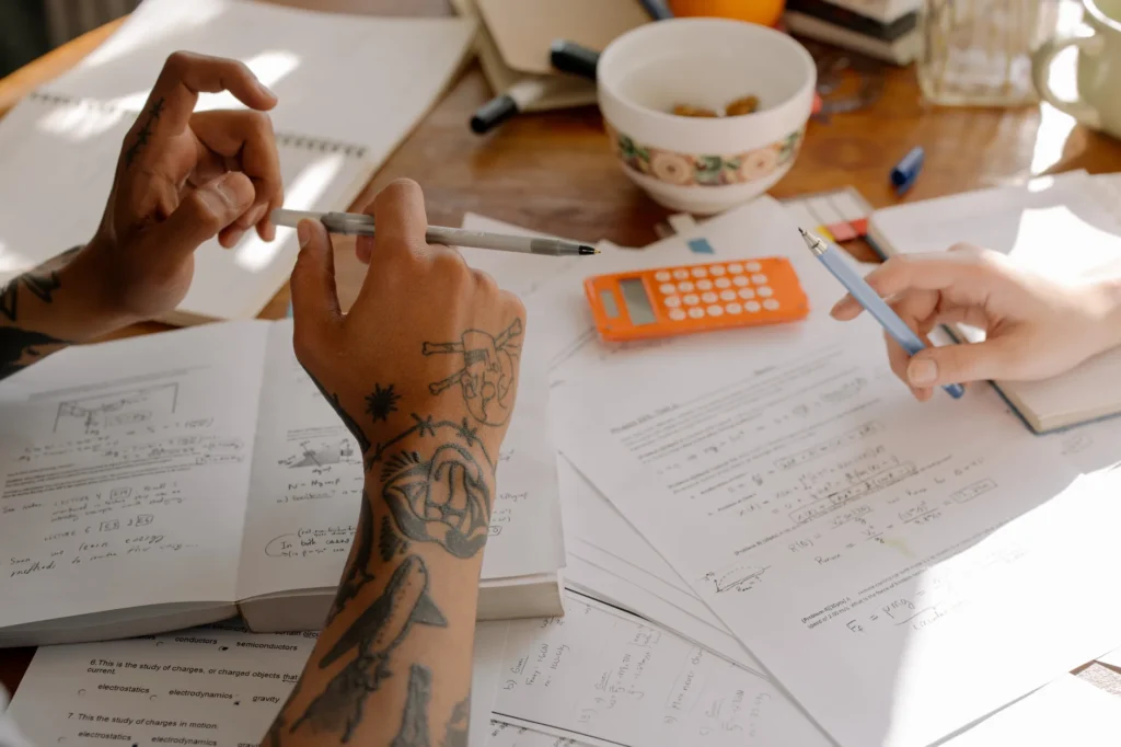 A home desk with a workbook, calculator, and calendar showing scheduled study blocks