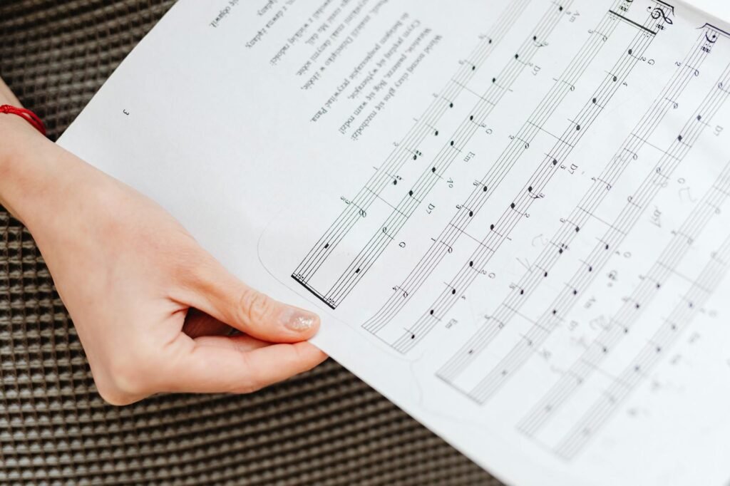 Hands, a music score, and a handwritten checklist on a practice desk.
