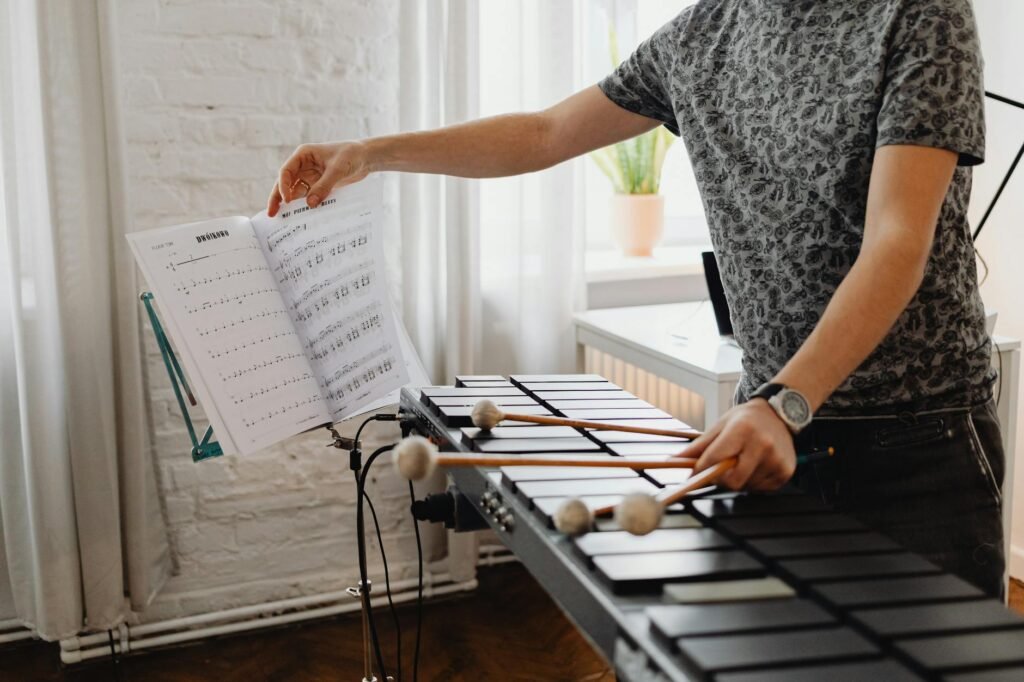A metronome and notebook next to marked sheet music on a music stand.