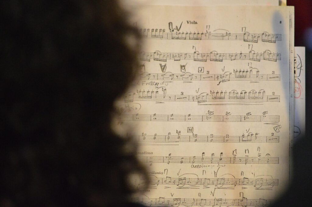 Marked sheet music beside a metronome and pencil in a practice room