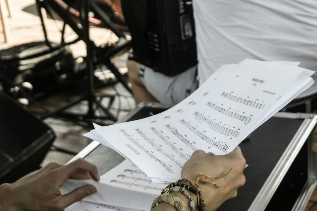 Hands marking problem sections on printed sheet music beside a phone tripod