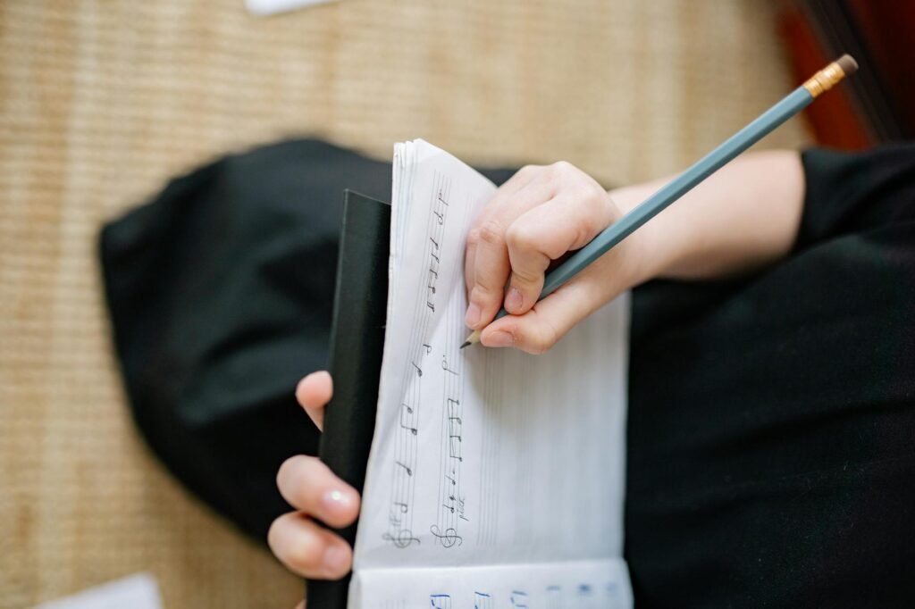 A handwritten practice log beside marked sheet music and a pencil