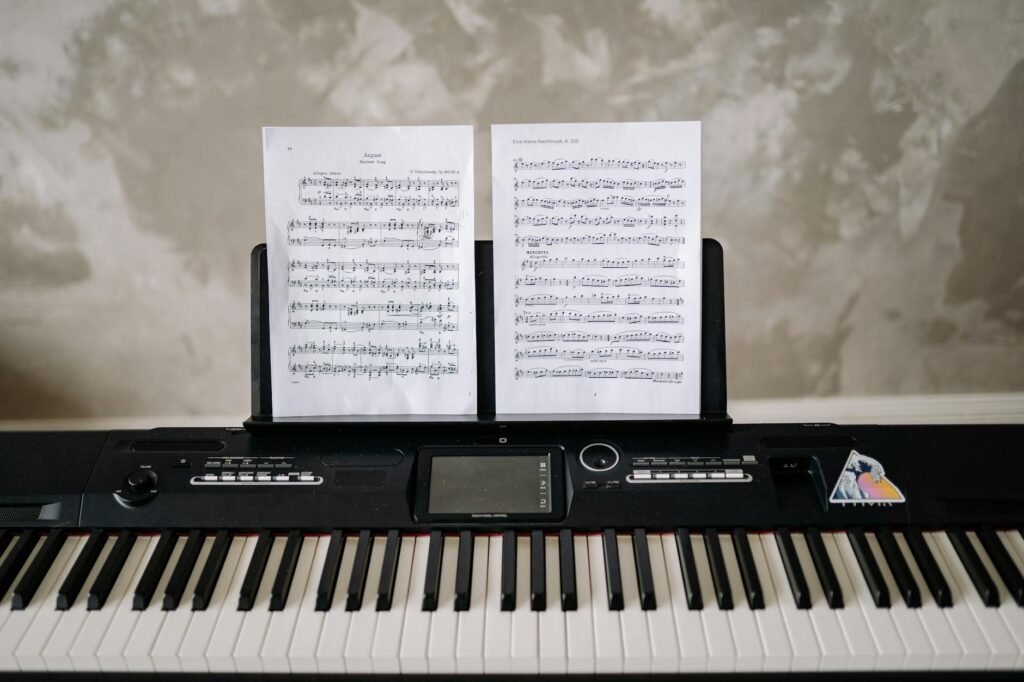 A musician's practice setup with sheet music, a notebook, and a metronome on a stand