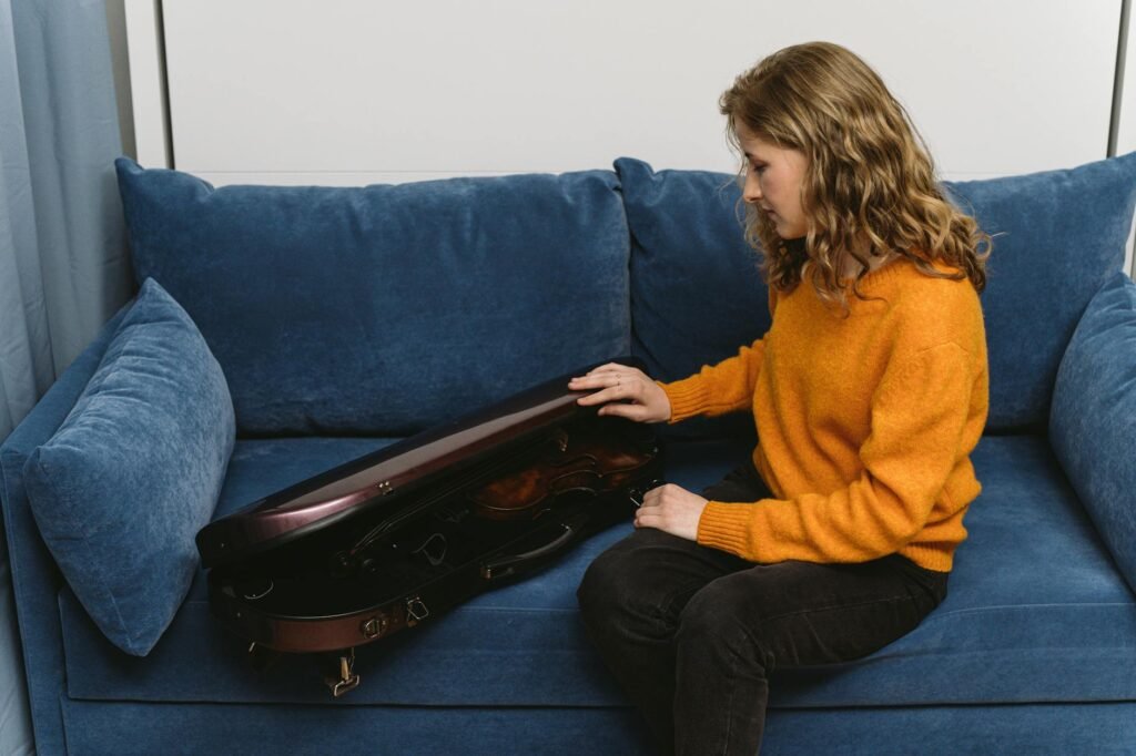 A quiet practice room with a music stand, instrument case, water bottle, and visible clock
