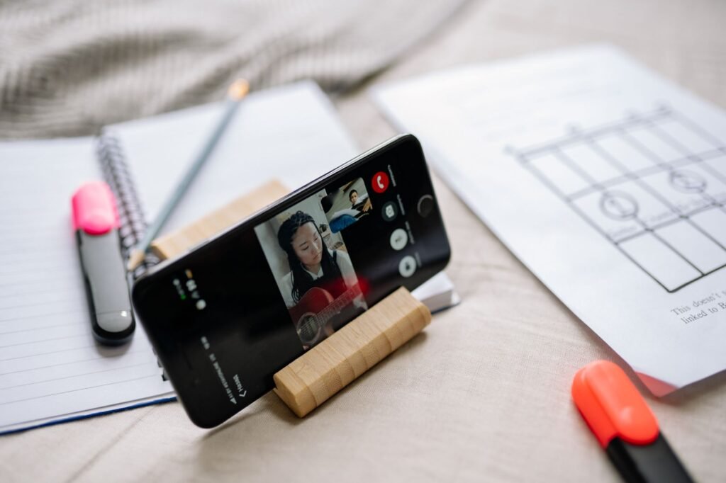 A musician reviews a phone recording next to marked-up sheet music and a metronome